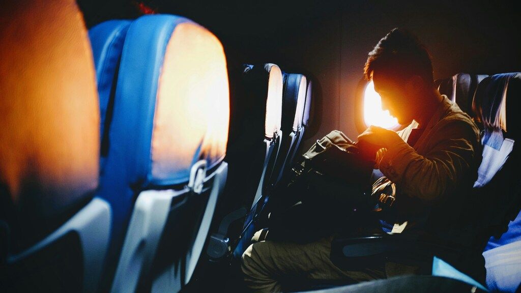 Mann schaut auf seinen Platz im Flugzeugsitz