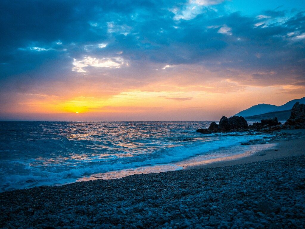 Albaniens Sehenswürdigkeiten: Ein Strand mit Felsen und Wasser