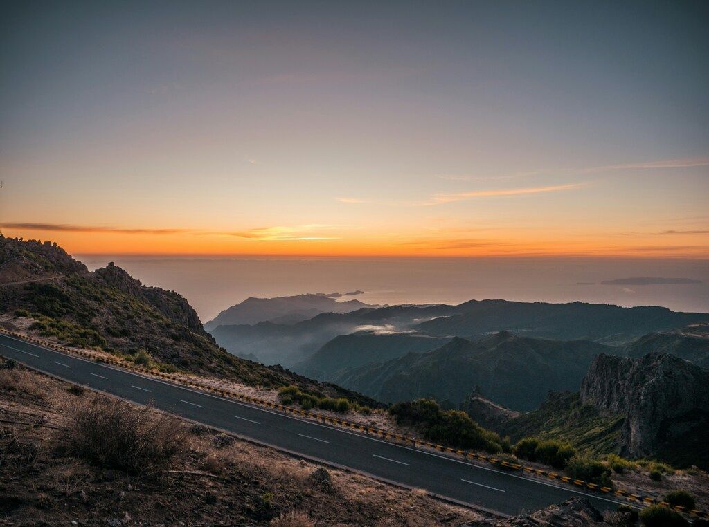 Schwarze Asphaltstraße in der Nähe der Berge bei Sonnenuntergang