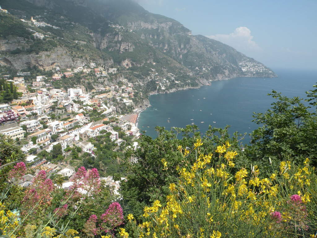 Blick auf die Küste von Amalfi mit bunten Häusern und blühenden Blumen im Vordergrund