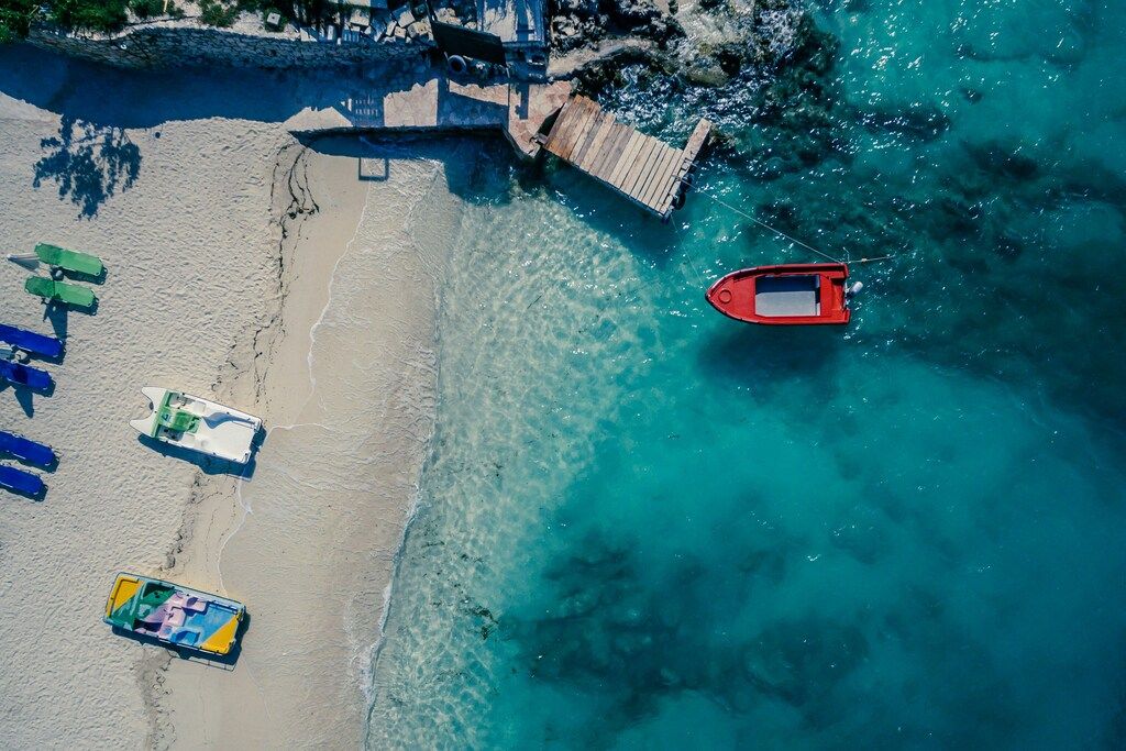 Albaniens Stränden: Rotes Boot auf einem Gewässer in der Nähe eines braunen Holzbretts