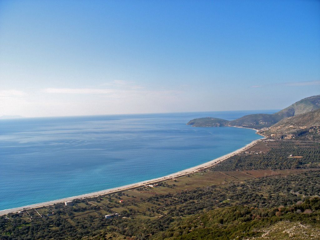 Albaniens Stränden: Küste der albanischen Riviera mit klarem, blauem Wasser und sanft geschwungenen Hügeln im Hintergrund