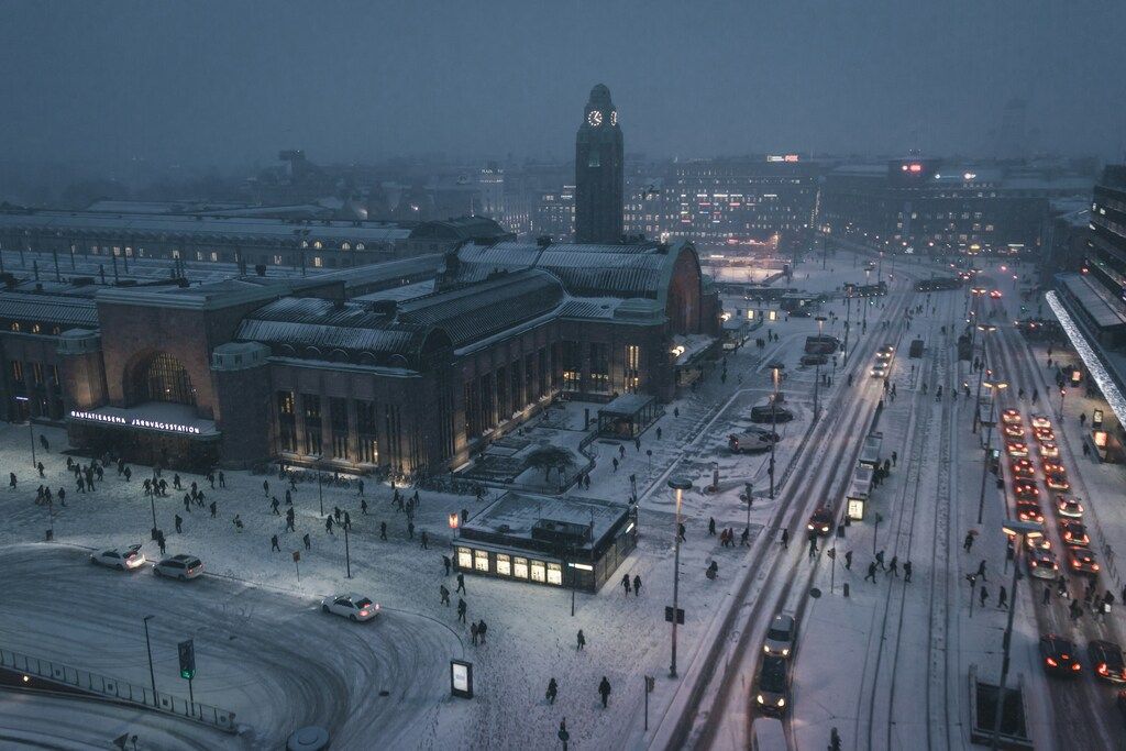 Nachtansicht des Hauptbahnhofs von Helsinki mit Schnee und Stadtverkehr.