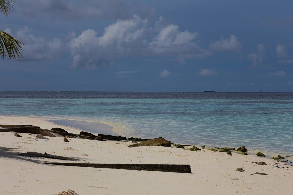 Sandstrand mit flachem, klarem Wasser und bewölktem Himmel