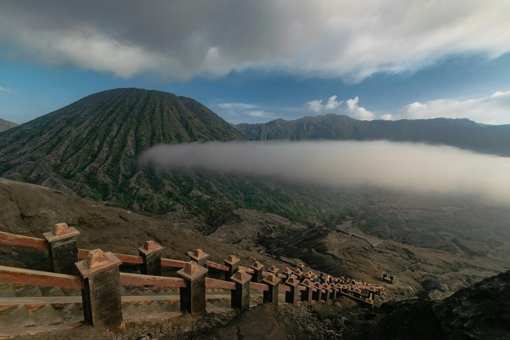 Indonesiens Sehenswürdigkeiten: Treppenweg mit einer Wolkenschicht und Bergen im Hintergrund.