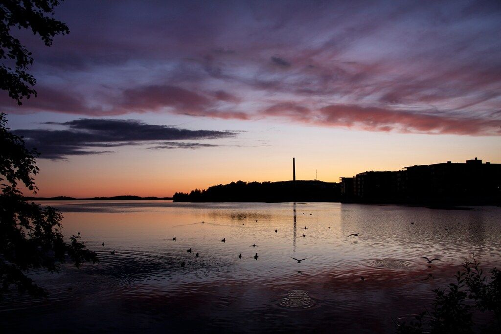 Abendhimmel über einem ruhigen See mit Vögeln.