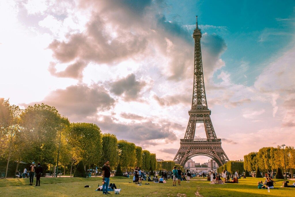 Der Eiffelturm in Paris bei Sonnenuntergang, umgeben von Menschen, die im Park entspannen