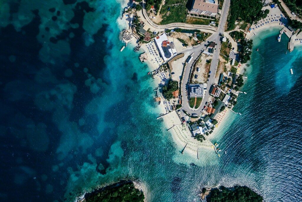 Blick von oben auf eine kleine Küstenstadt mit türkisfarbenem Wasser und Sandstränden