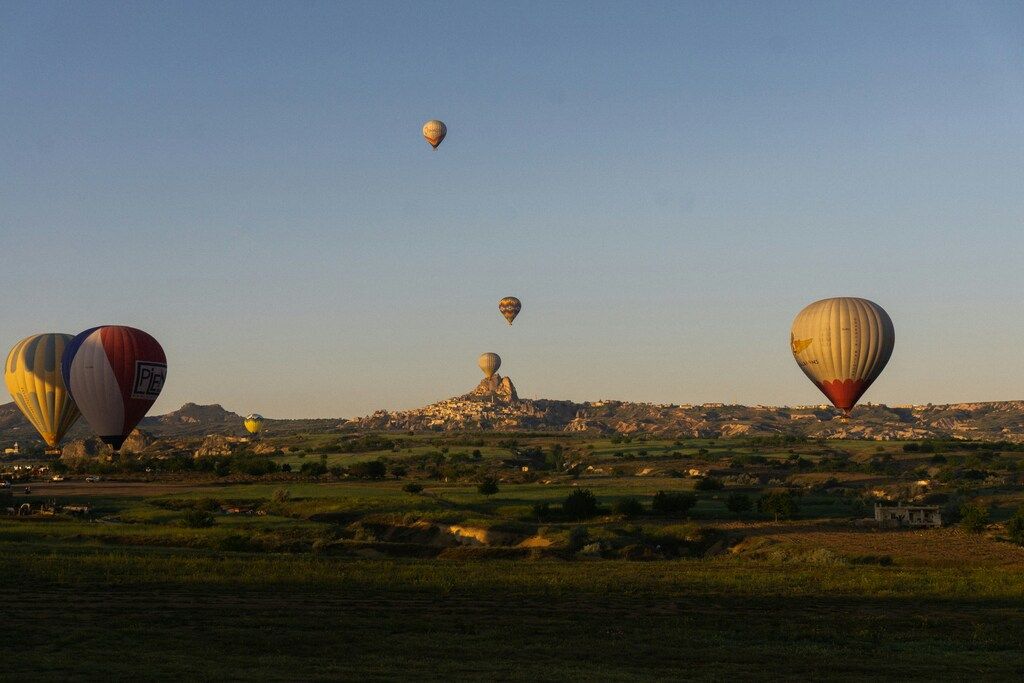 Mehrere bunte Heißluftballons schweben über der Landschaft von Kappadokien bei Sonnenaufgang