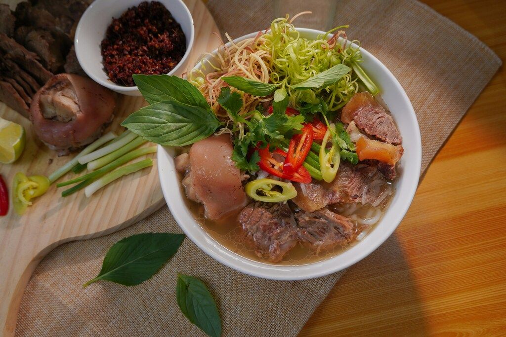 Vietnamesisches Essen: white ceramic bowl with soup and green leaves