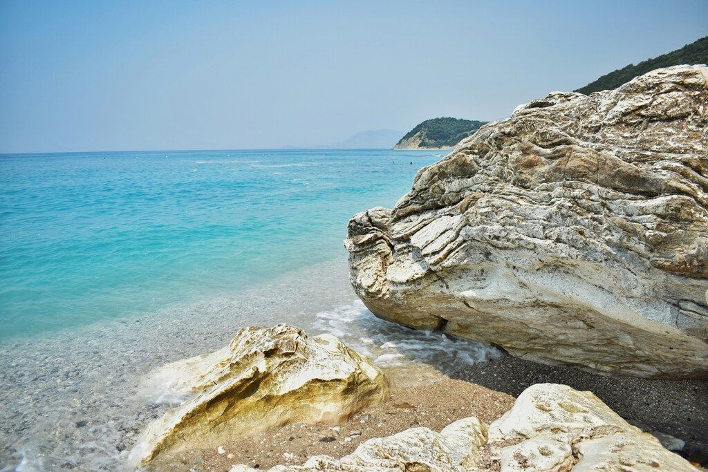 Albaniens Stränden: Ein großer Felsen, der oben auf einem Strand am Meer liegt