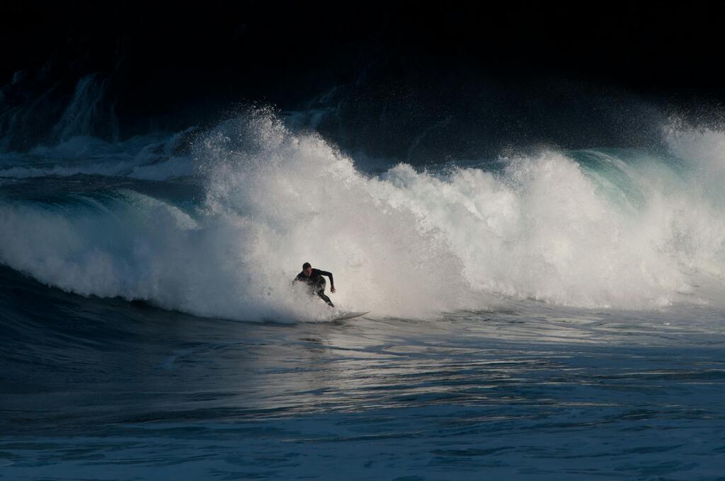 Surfer in Aktion, kämpft gegen eine massive Welle vor der Küste Teneriffas.