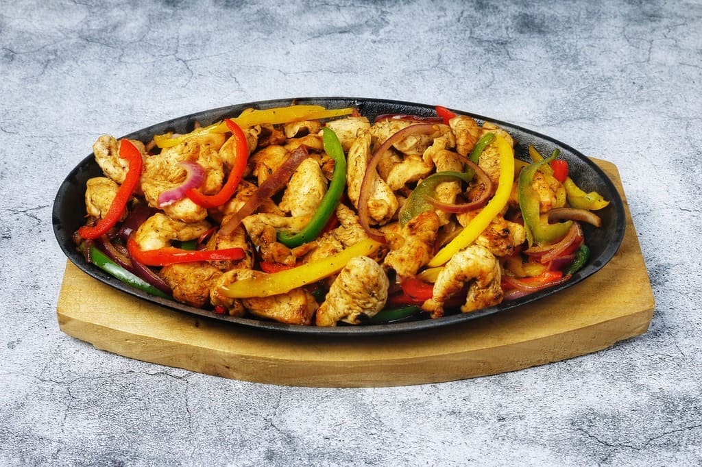 Heiße Fajitas mit Paprika und Hähnchen auf einem Servierteller.