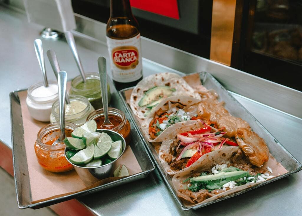 Tablett mit Tacos, Limettenscheiben und verschiedenen Soßen in einem mexikanischen Restaurant.