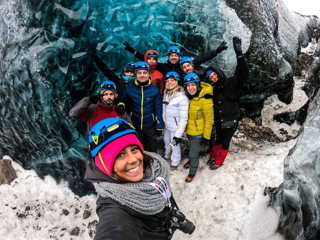 Eine Gruppe von Reisenden mit Helmen bei einer geführten Tour in einer Gletscherhöhle in Island, organisiert von WeRoad.