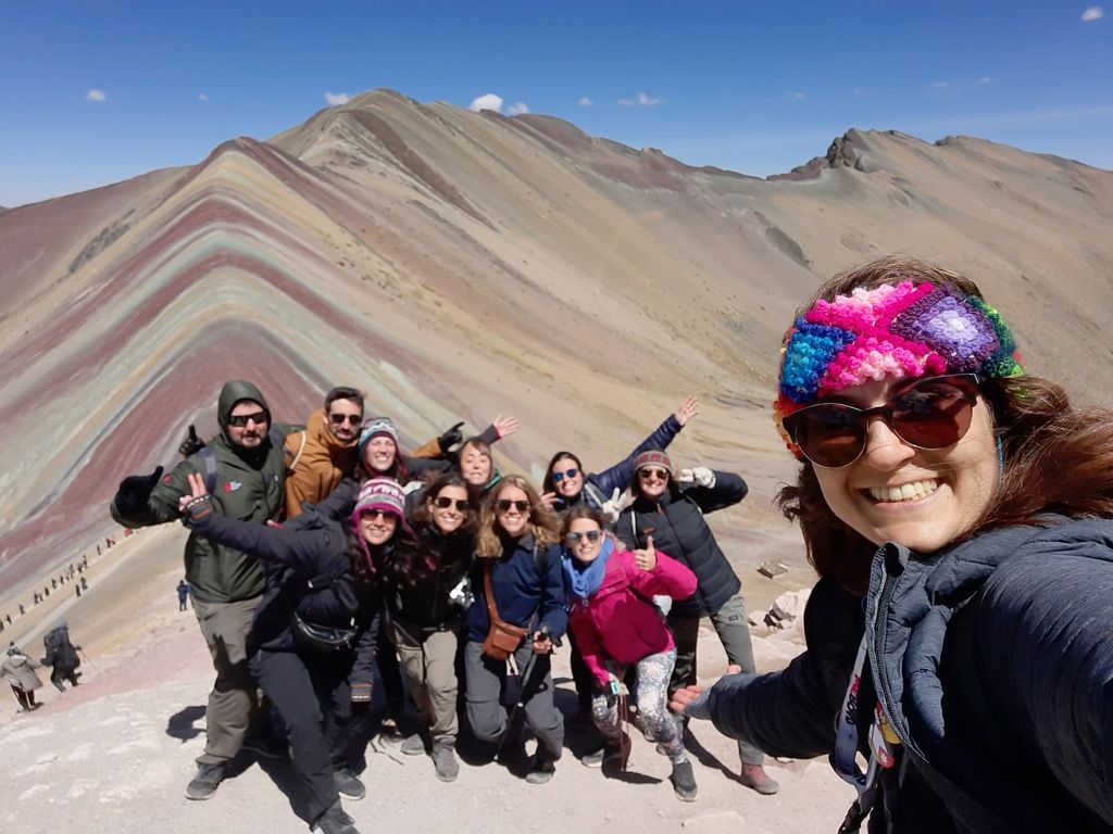 Eine WeRoad-Gruppe posiert vor dem Regenbogenberg in Peru während einer organisierten Gruppenreise.