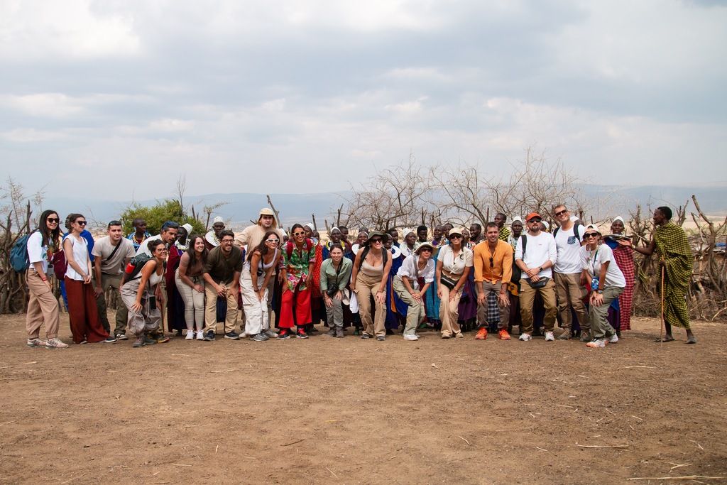 Eine von WeRoad organisierte Gruppenreise nach Tansania, mit Teilnehmern, die zusammen mit einer lokalen Gemeinschaft in einer authentischen afrikanischen Landschaft posieren.