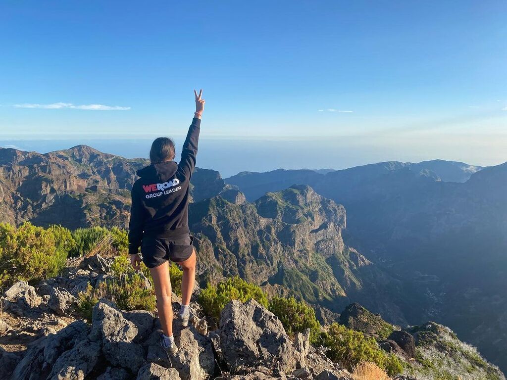 Eine Reisende auf einem Berg in Madeira, die den Blick auf die Täler und das Meer genießt.