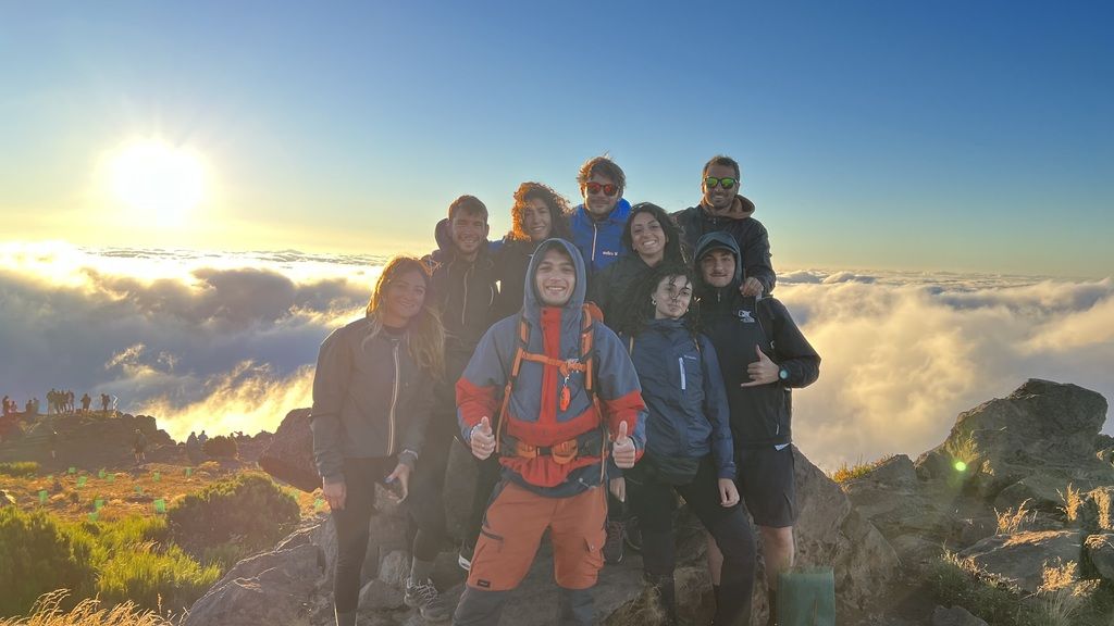 WeRoad-Gruppe genießt den Sonnenaufgang über den Wolken während einer Wanderung in Madeira.