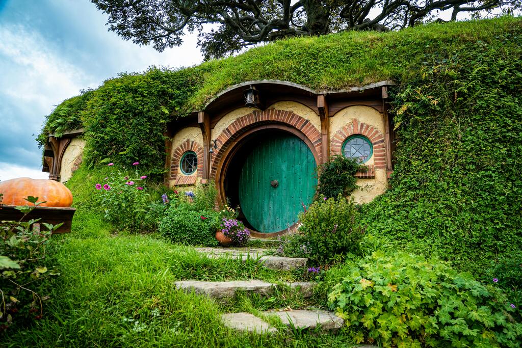 Das Hobbiton-Filmset mit ikonischen, grasbedeckten Hobbit-Häusern und blühendem Garten.