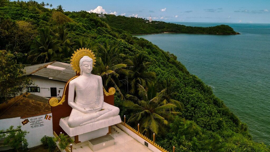 Weiße Buddha-Statue auf einem Hügel mit Blick auf das Meer in Sri Lanka