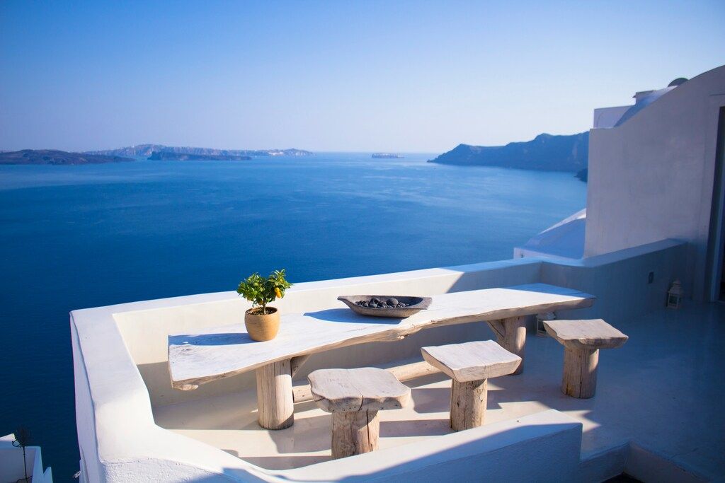 Terrasse mit weißem Tisch und Blick auf das blaue Meer in Santorin