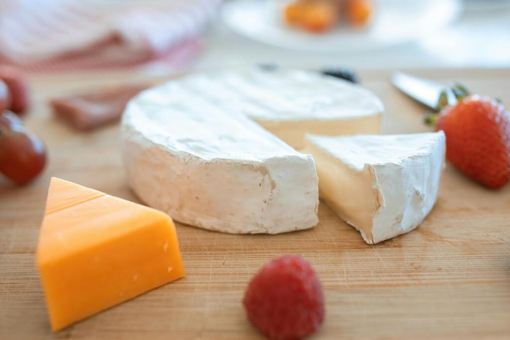 Französischer Camembert und Cheddar auf einem Schneidebrett mit Beeren.