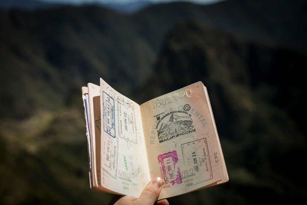Geöffneter Reisepass mit Stempeln vor einer verschwommenen Berglandschaft