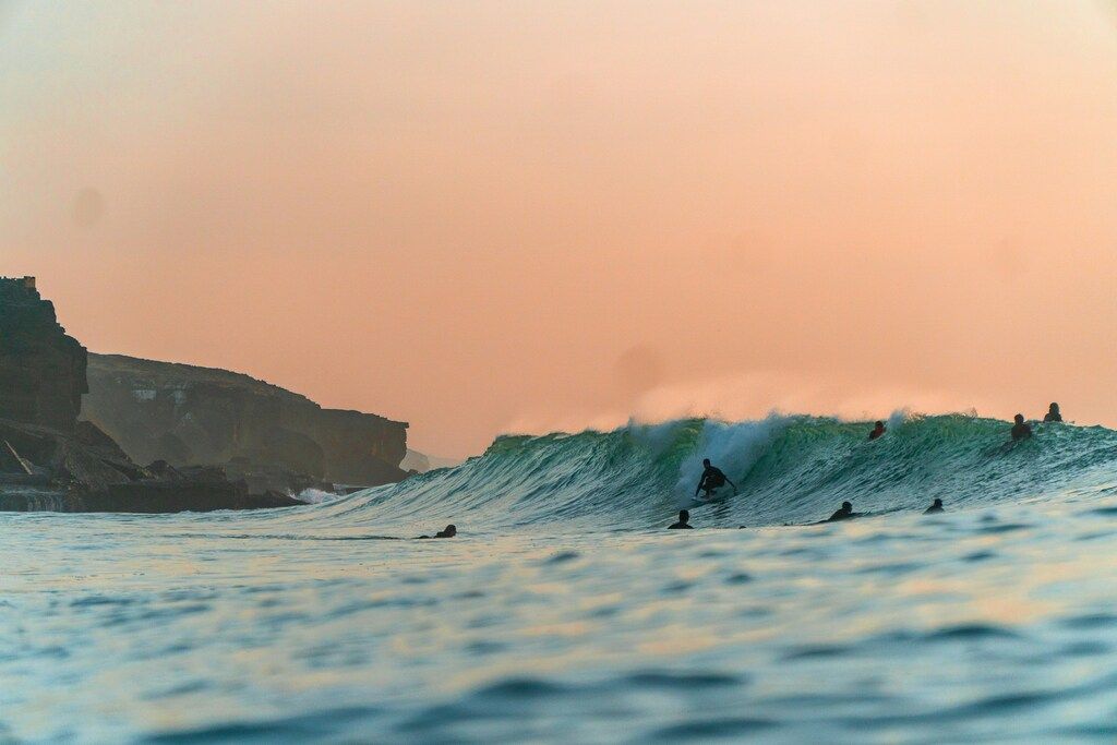 Mehrere Surfer bei Sonnenuntergang im Meer.