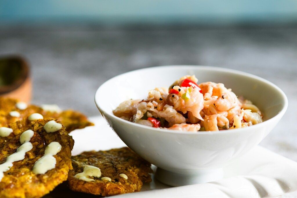 Frischer Garnelen-Ceviche serviert mit knusprigen Patacones und einem cremigen Dip.