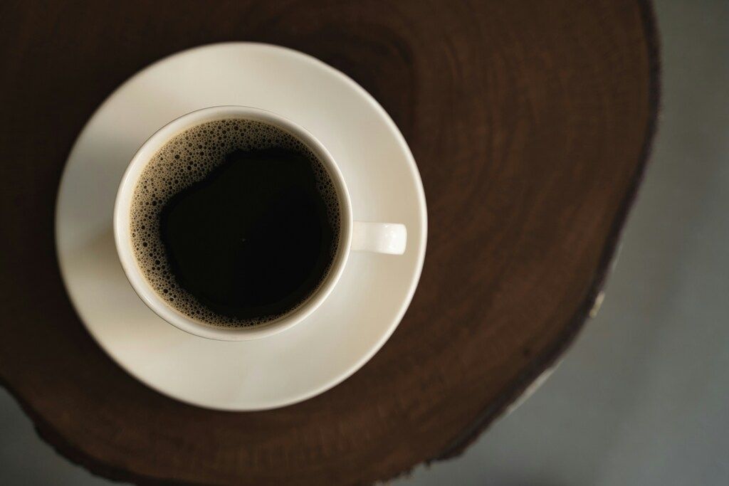 Tasse frisch gebrühter schwarzer Kaffee auf einem Holztisch.