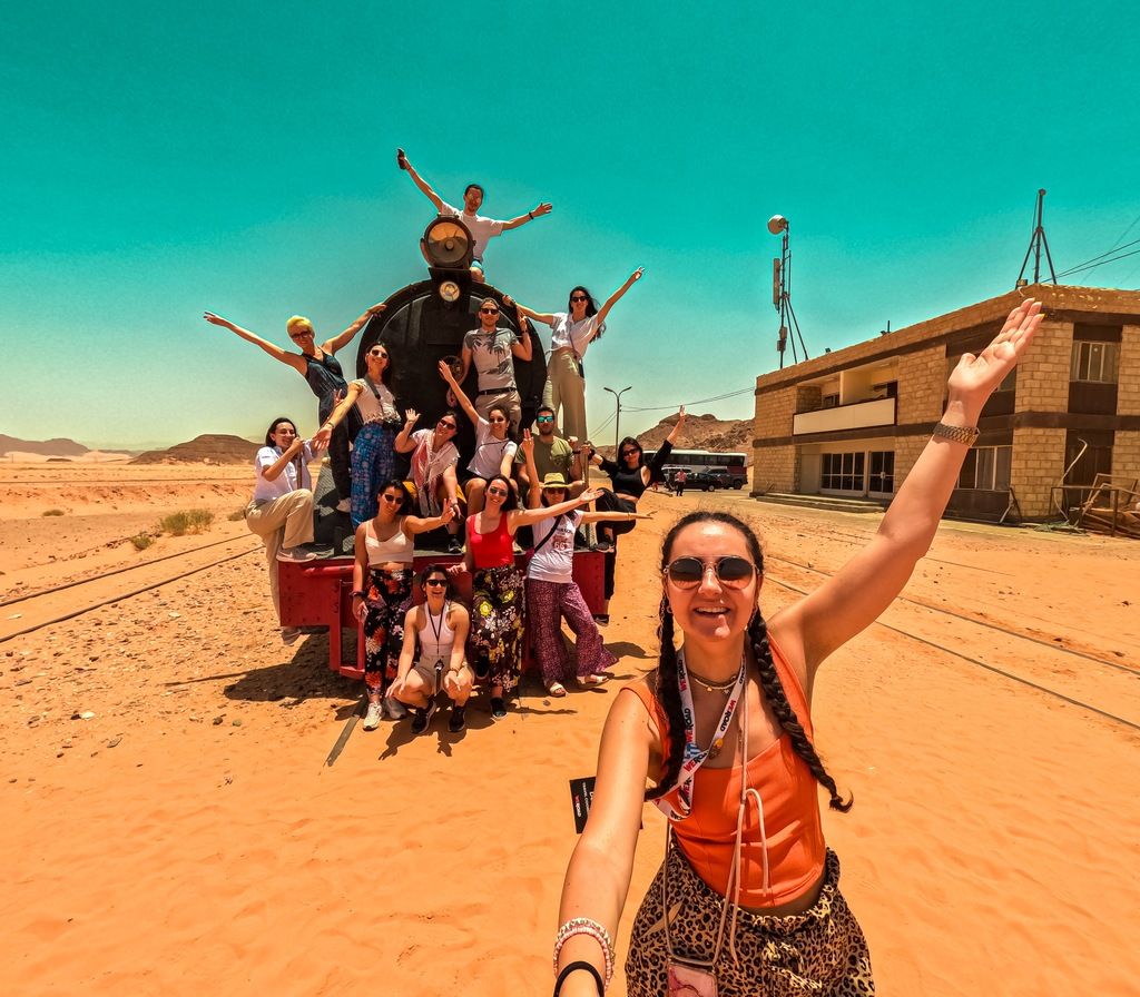 Fröhliche Reisegruppe posiert auf einer alten Dampflok in der Wüste von Jordanien.
