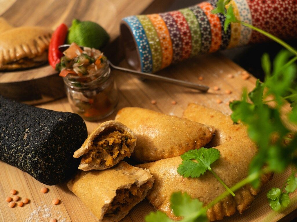 Hausgemachte Empanadas mit würziger Füllung, serviert mit Salsa und Koriander.