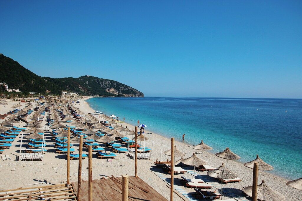 Sonnenliegen und Strohdächer am Strand von Dhermi, Albanische Riviera
