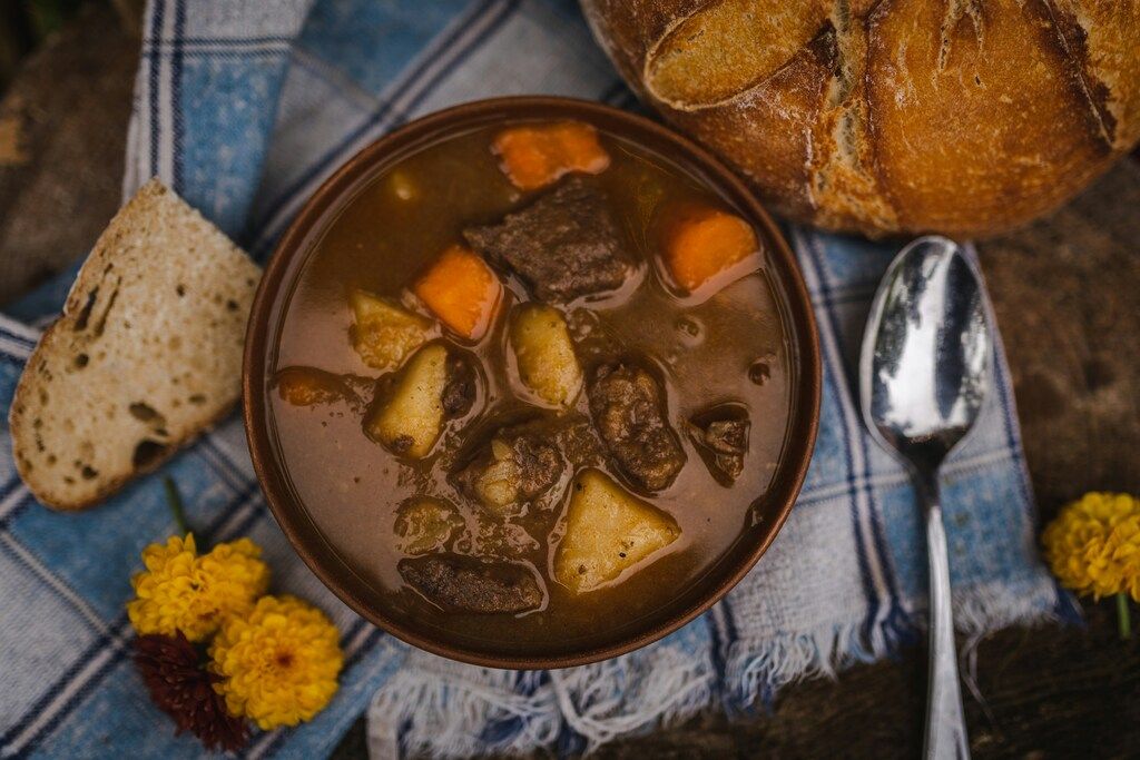 Herzhaftes Eintopfgericht mit Kartoffeln, Karotten und Fleisch, serviert mit Bauernbrot