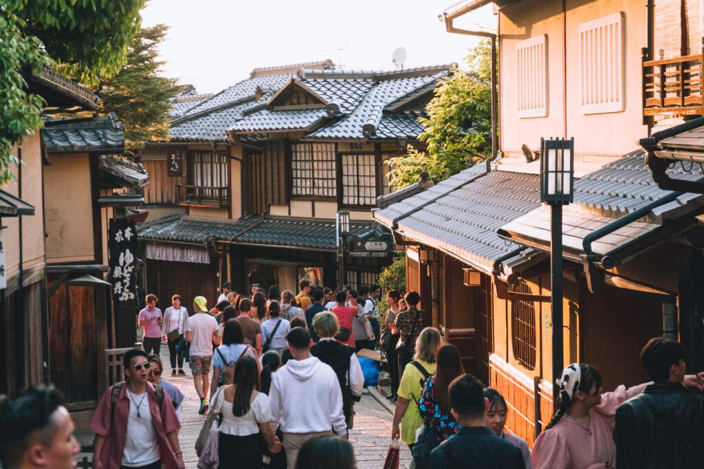 Touristen und Einheimische spazieren durch eine belebte Straße in Kyoto, Japan, gesäumt von traditionellen Gebäuden.