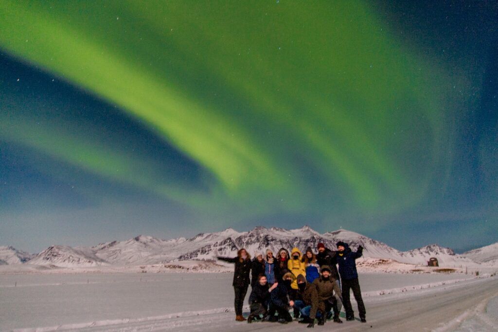 WeRoad-Reisegruppe beobachtet die Nordlichter in Island unter einem spektakulären Himmel voller Polarlichter