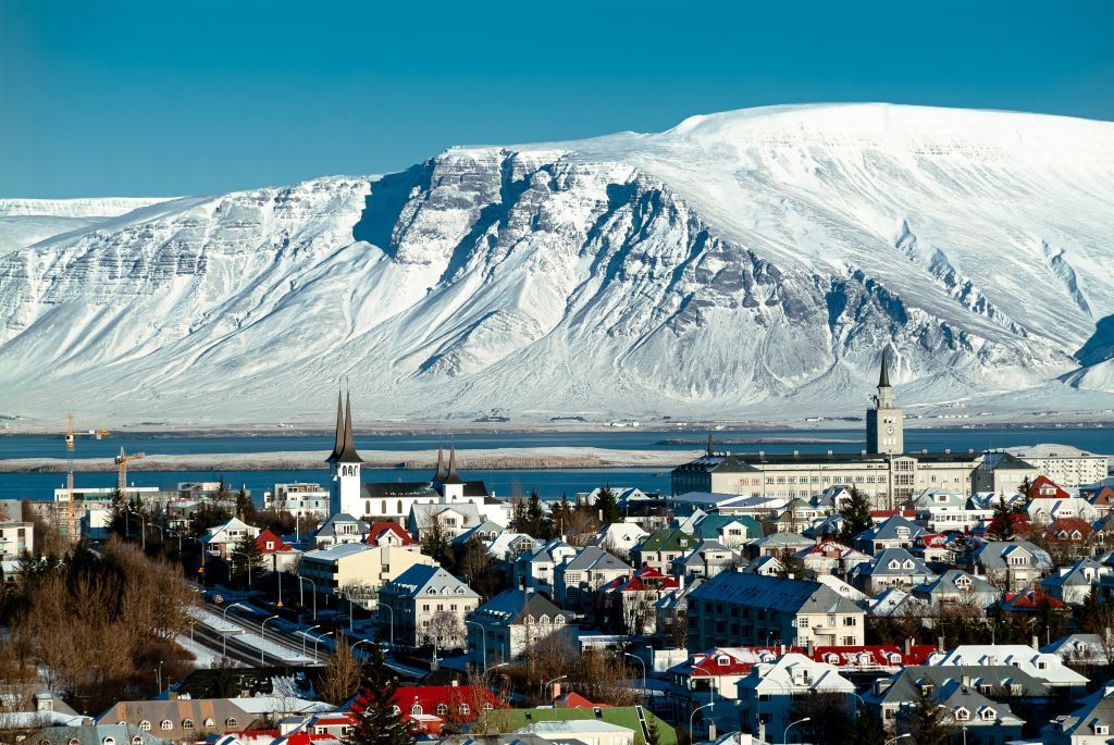 Panoramablick auf das Zentrum von Reykjavik: bunte Dächer vor dem majestätischen, schneebedeckten Berg Esja.