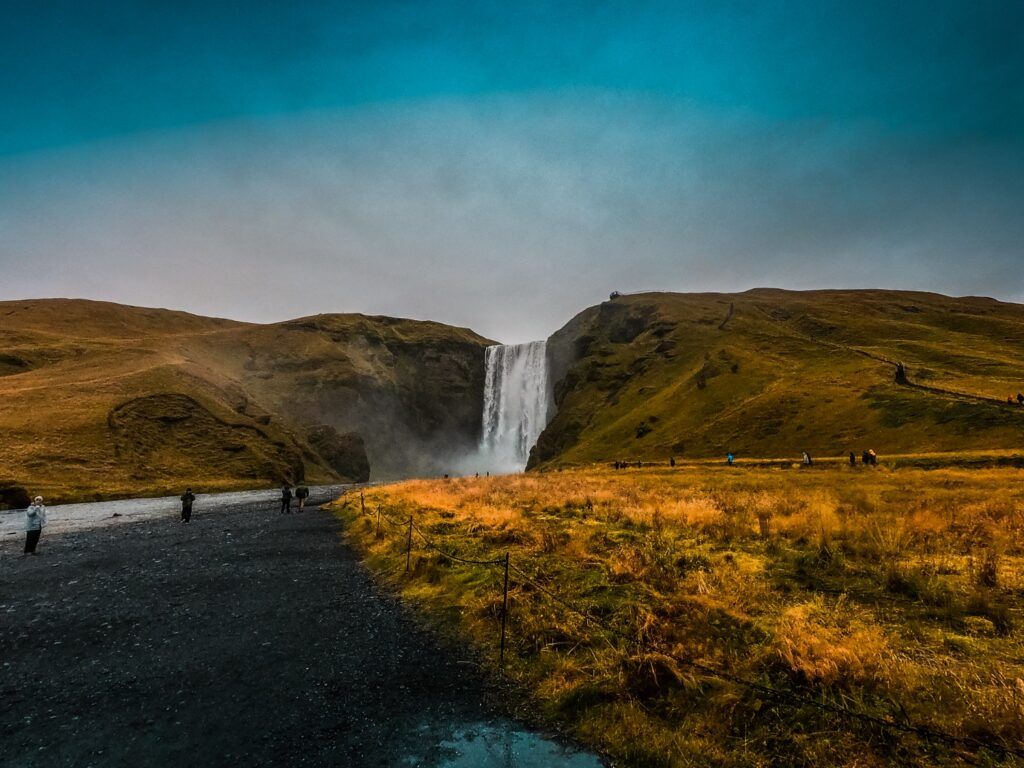 Skógafoss Wasserfall in Island, umgeben von goldbrauner Landschaft.