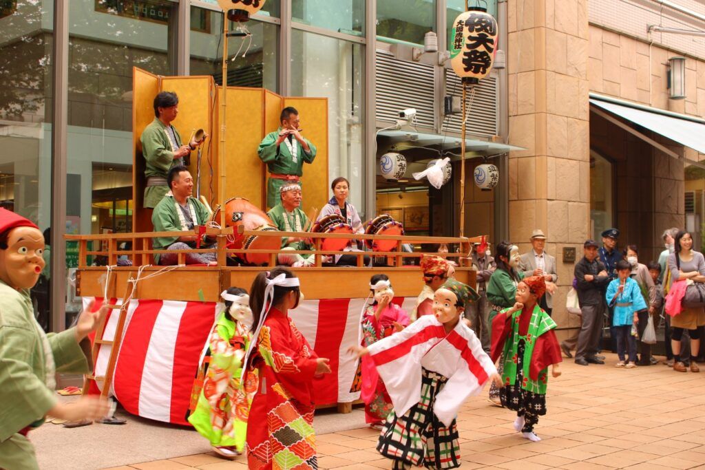 Lebendiges Matsuri-Frühlingsfest in Japan während der Golden Week, mit traditionellen Tänzern, Masken und Trommlern.