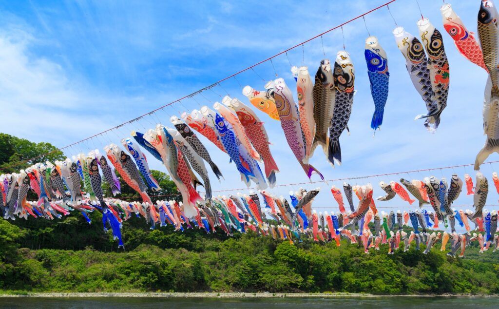 Hunderte bunter Koinobori-Karpfenfahnen hängen über einem Fluss und feiern den Kodomo no Hi während der Golden Week.