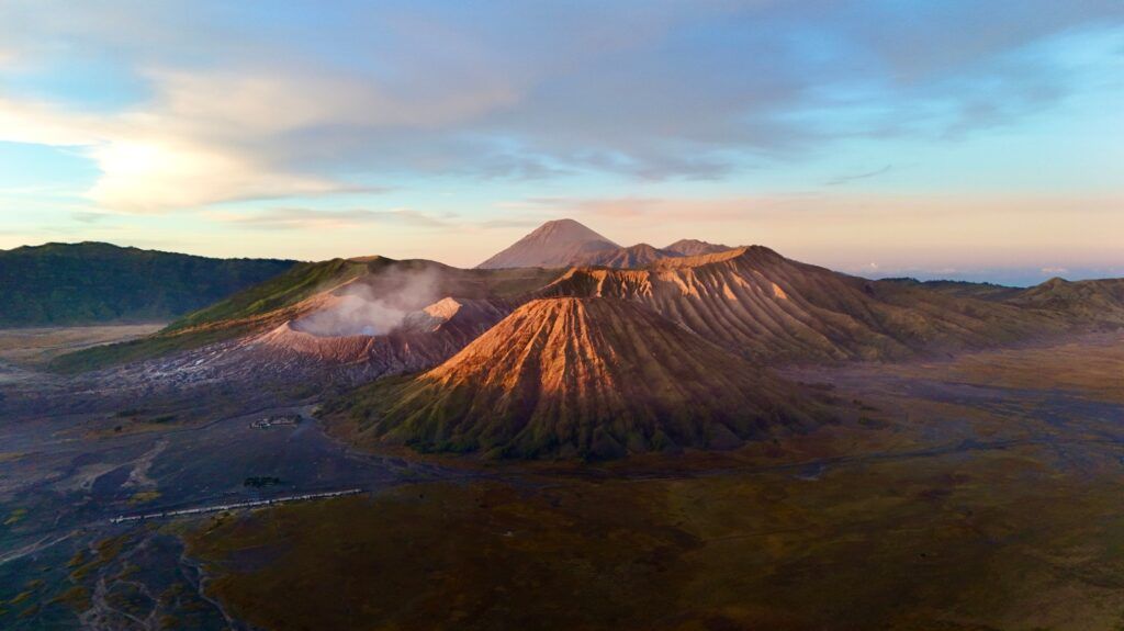 Panoramablick auf den rauchenden Mount Bromo Vulkan und die umliegende Sea of Sand Landschaft bei Sonnenaufgang.