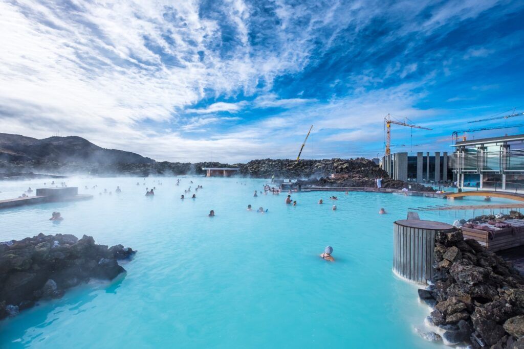 Besucher baden in der Blauen Lagune, einem berühmten geothermischen Spa in Island mit hellblauem, dampfendem Wasser.