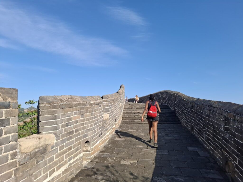 Hiker with red rucksack on a steep section of the Great Wall of China.