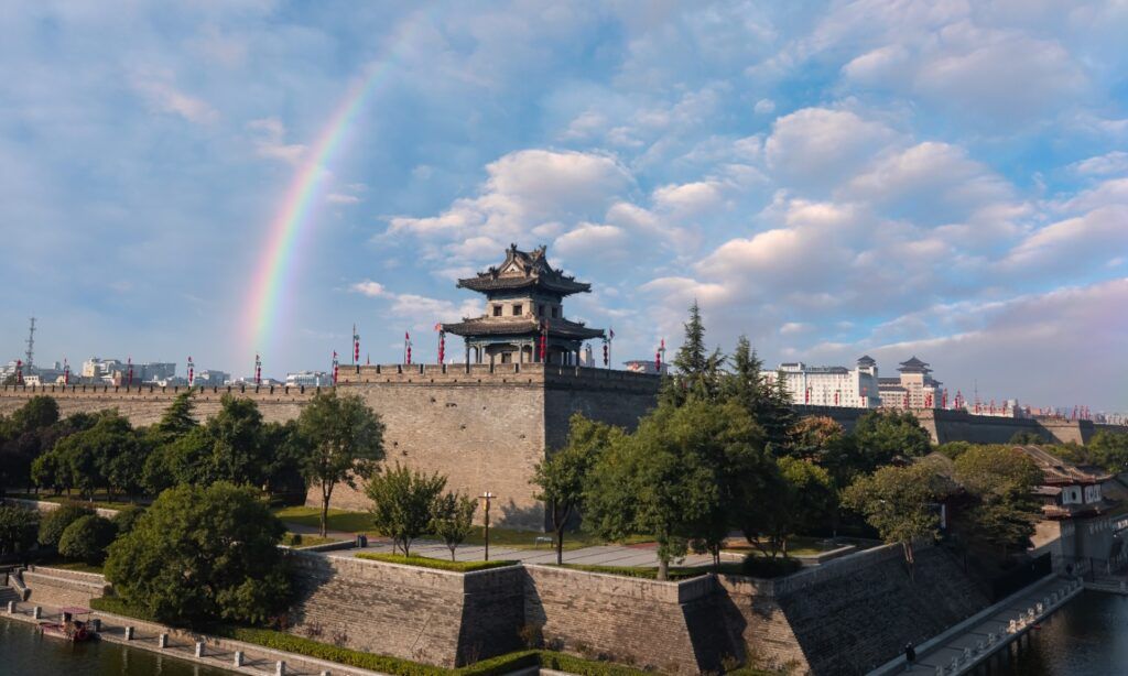 Die historische Stadtmauer von Xi'an mit einem Wachturm und einem Regenbogen.