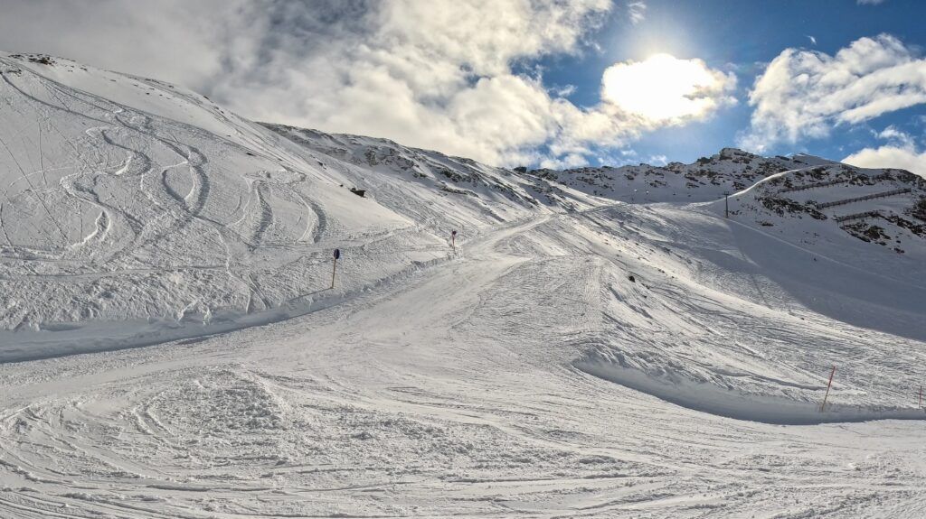 Hochalpine Piste mit viel Schnee unter strahlendem Himmel in Sölden.