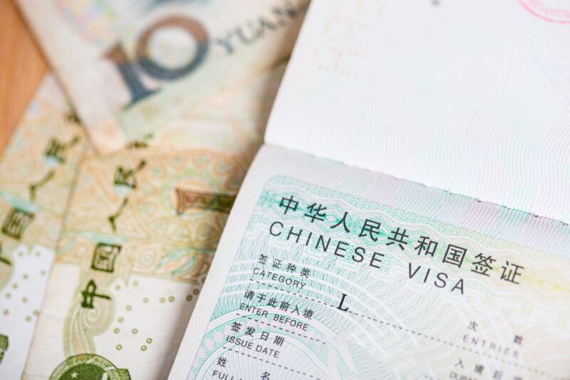 Chinesisches Visum in einem Reisepass, daneben liegen Yuan-Banknoten.