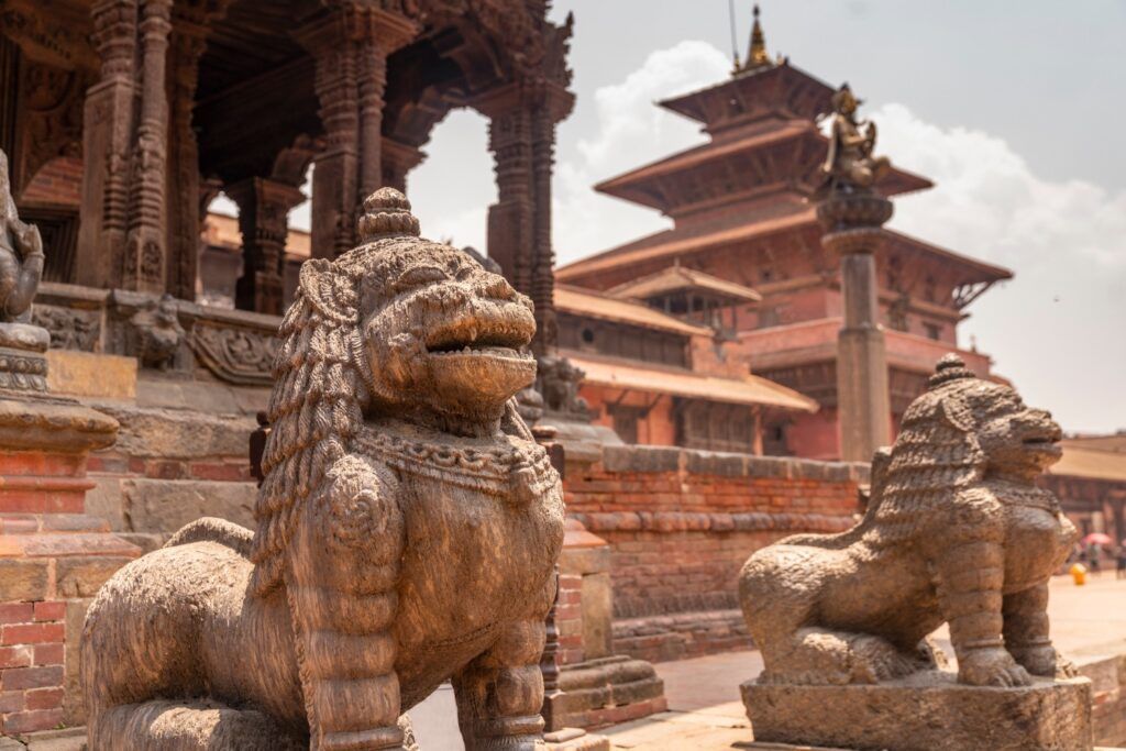 Zwei antike steinerne Löwenstatuen bewachen den Eingang zu einem Tempel am Patan Durbar Square in Nepal.