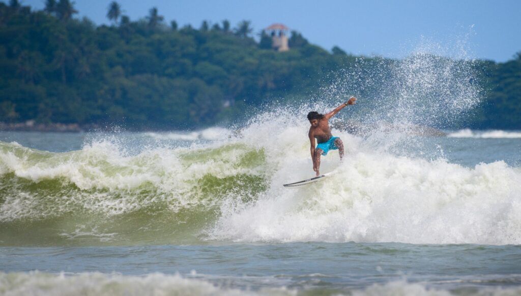 Ein Surfer reitet eine große, schäumende Welle vor der Küste von Weligama in Sri Lanka.